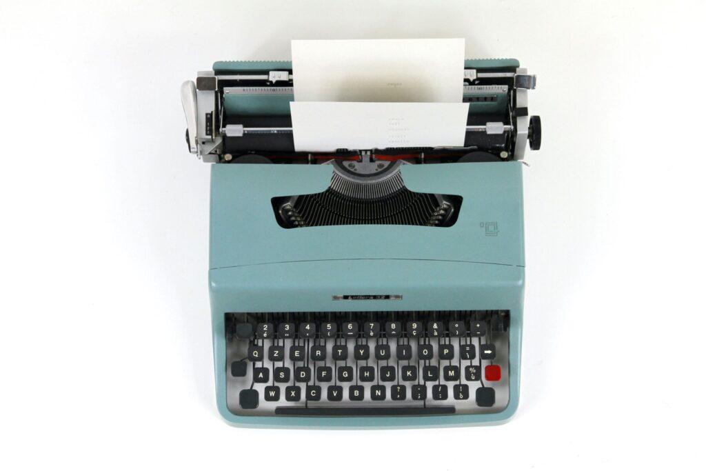 Teal-colored vintage typewriter against a white background.